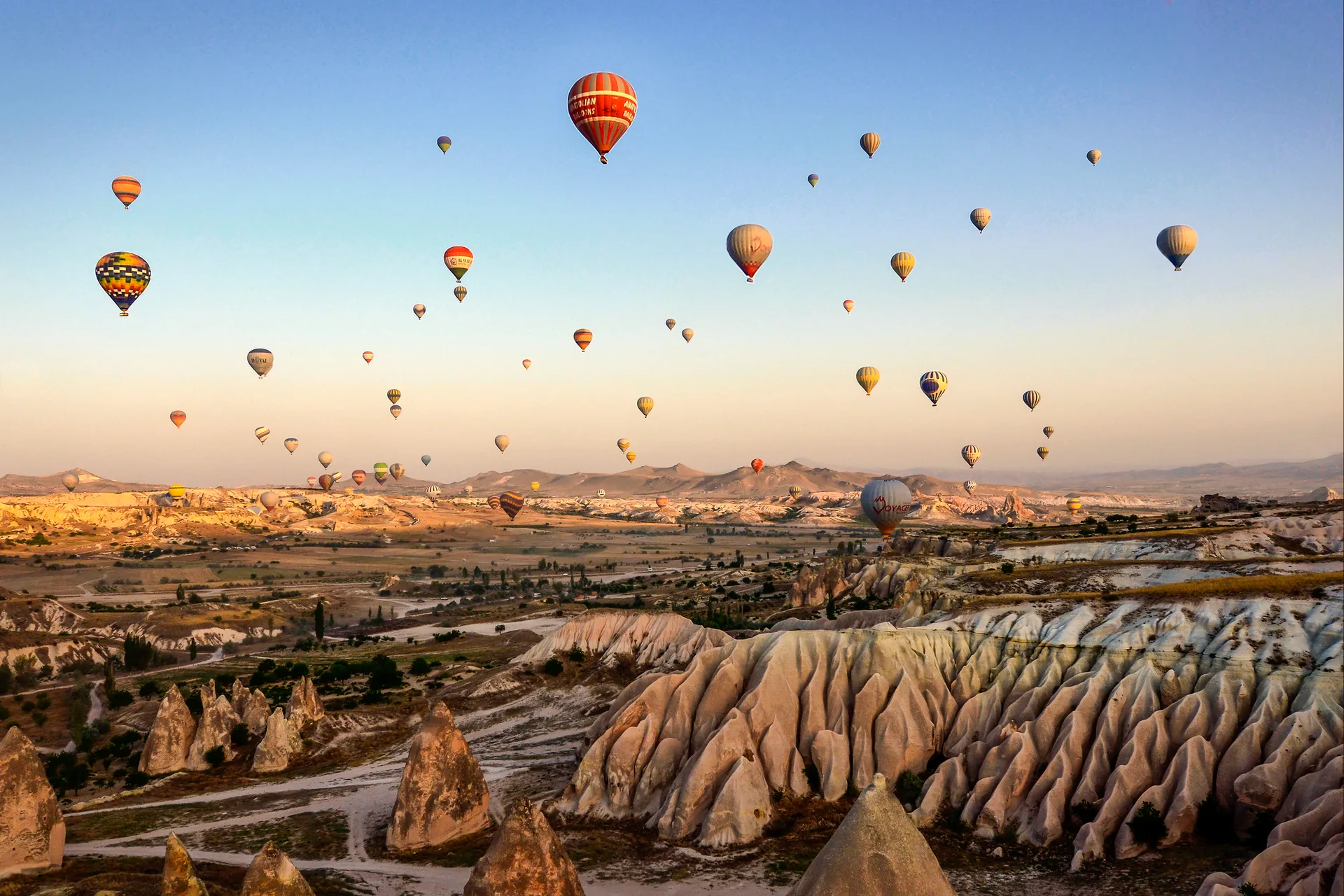 Dezenas de balões coloridos no céu do amanhecer sobre as formações rochosas da Capadócia, na Turquia