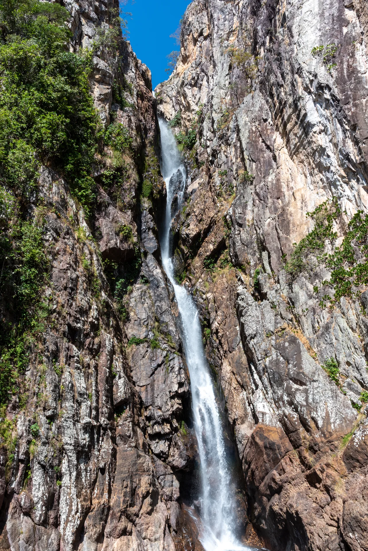 Cachoeira estreita descendo entre altos paredões de pedra, na Cachoeira Veredas, em Cavalcante