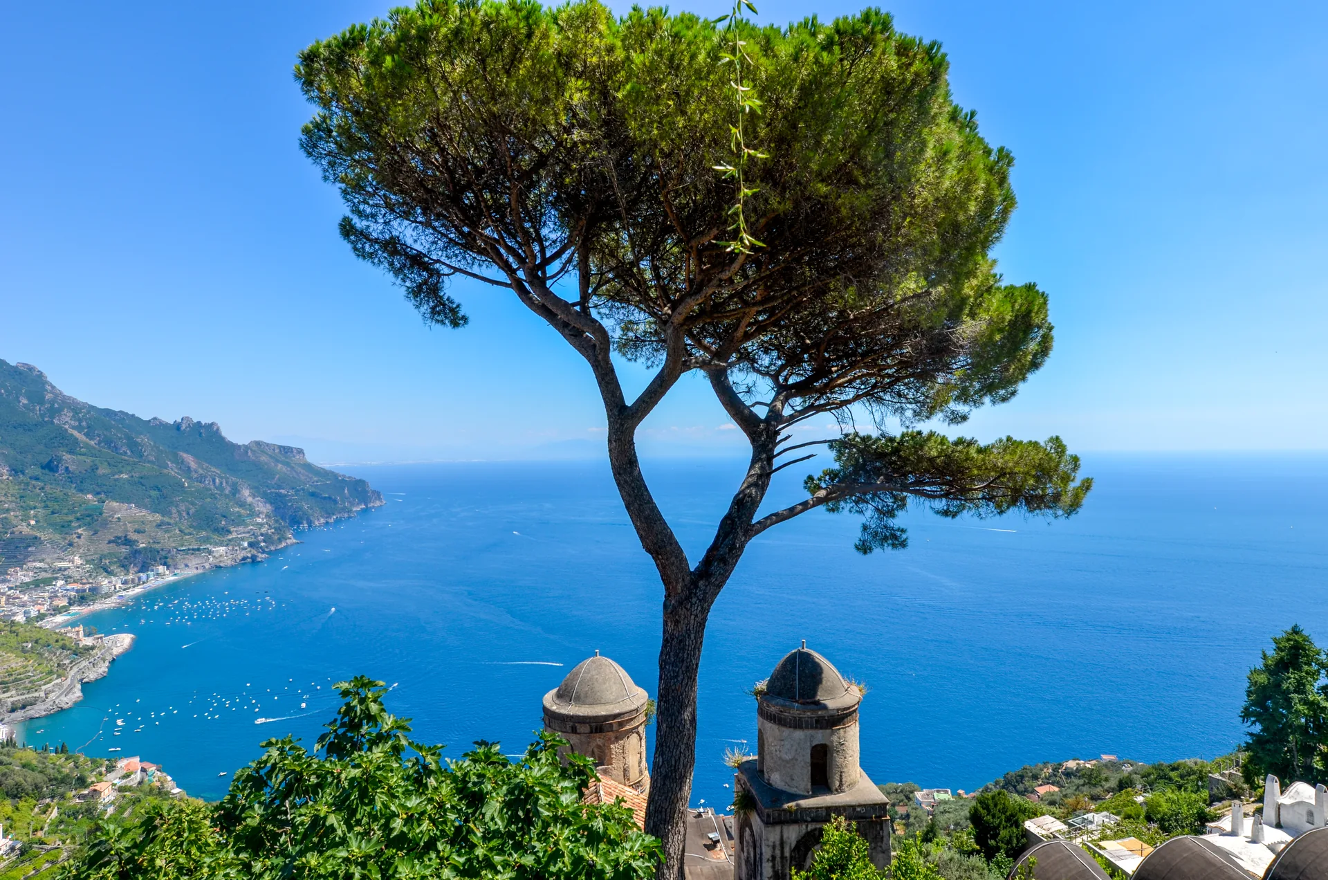 Pinheiro-manso e duas torres da Villa Rufolo diante do mar azul da Costa Amalfitana, em Ravello